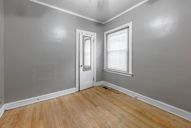 empty room with ornamental molding, baseboards, and hardwood / wood-style floors