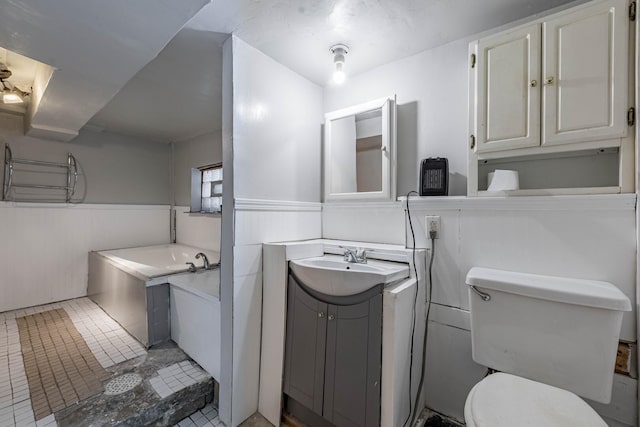 full bath featuring toilet, a wainscoted wall, a bath, and vanity