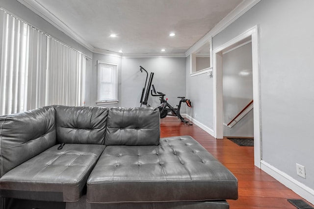 living area with baseboards, wood finished floors, visible vents, and crown molding