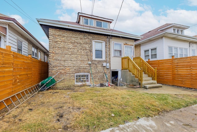 rear view of property with brick siding, fence, and a lawn