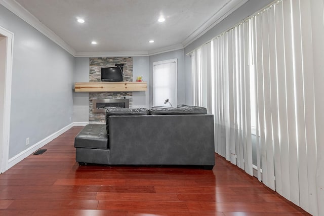 living area with crown molding, a fireplace, visible vents, wood finished floors, and baseboards