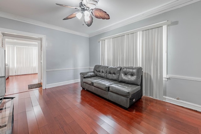 living area featuring crown molding, baseboards, ceiling fan, and wood finished floors