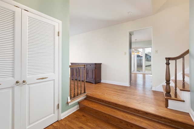 corridor with stairway, wood finished floors, and baseboards