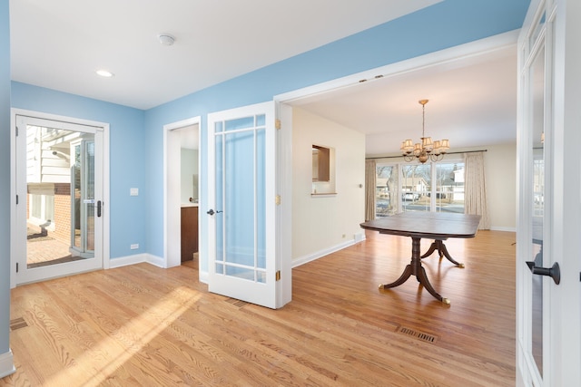 interior space with visible vents, an inviting chandelier, baseboards, and light wood-style floors