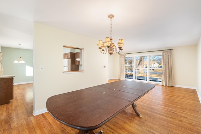 dining space with light wood-style flooring, baseboards, and a chandelier