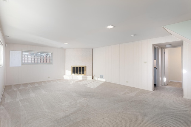 unfurnished living room with light carpet, visible vents, and a fireplace