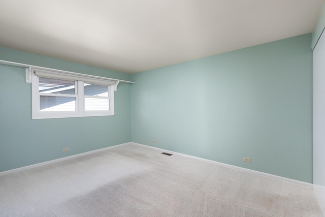 carpeted empty room featuring baseboards and visible vents