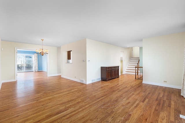 unfurnished living room with a notable chandelier, baseboards, light wood-style floors, and visible vents