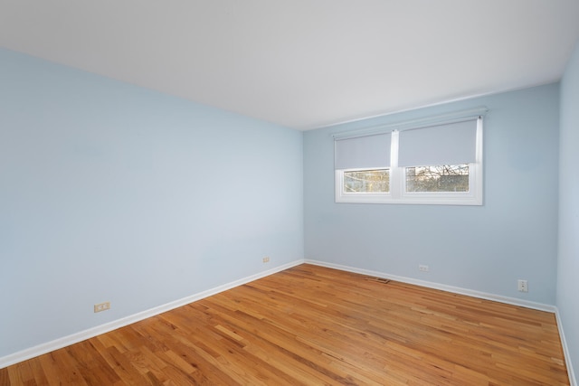 unfurnished room featuring light wood-type flooring, baseboards, and visible vents