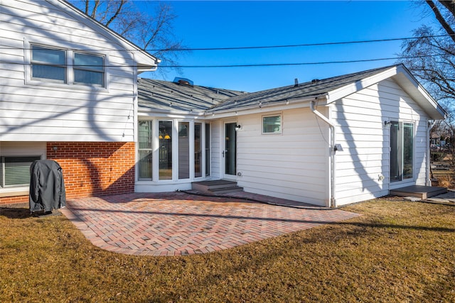 back of property with a patio, a yard, a shingled roof, entry steps, and brick siding