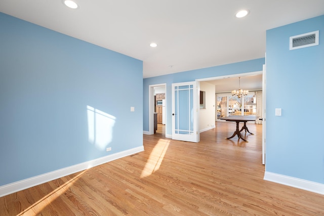 unfurnished living room with baseboards, visible vents, an inviting chandelier, recessed lighting, and light wood-type flooring