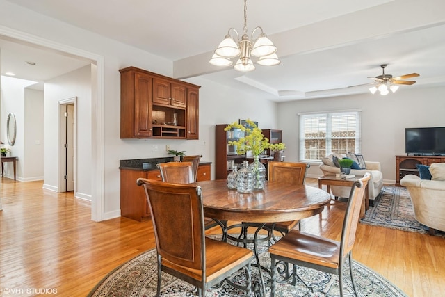 dining space featuring light wood-type flooring, baseboards, and ceiling fan with notable chandelier