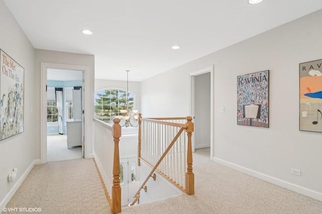 hall with carpet floors, recessed lighting, a notable chandelier, and an upstairs landing