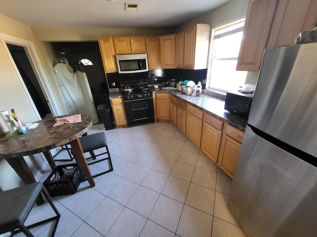 kitchen with dark countertops, black appliances, light tile patterned floors, and visible vents