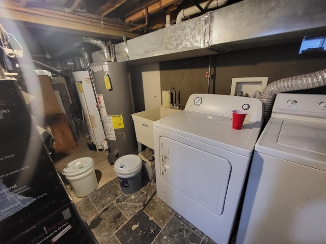 laundry area featuring laundry area, stone finish flooring, water heater, separate washer and dryer, and a sink