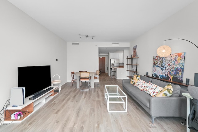 living area with light wood-type flooring, baseboards, visible vents, and track lighting