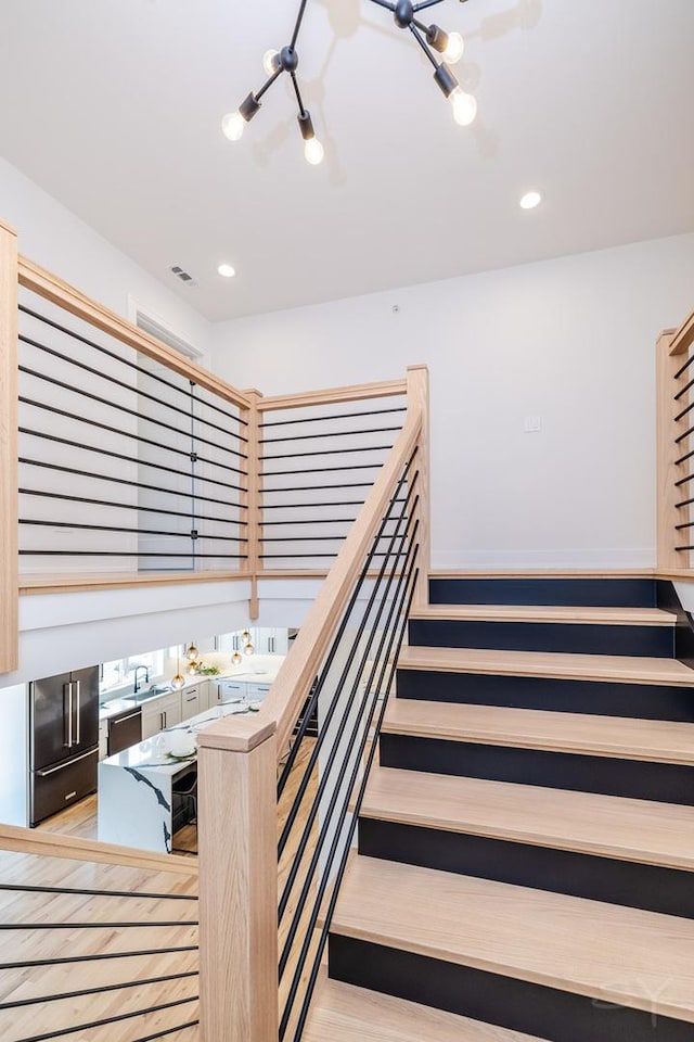 stairway with recessed lighting and wood finished floors