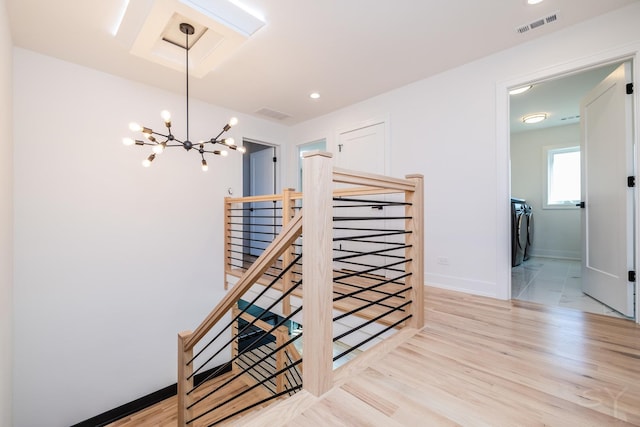 corridor featuring visible vents, an upstairs landing, wood finished floors, washer and dryer, and baseboards