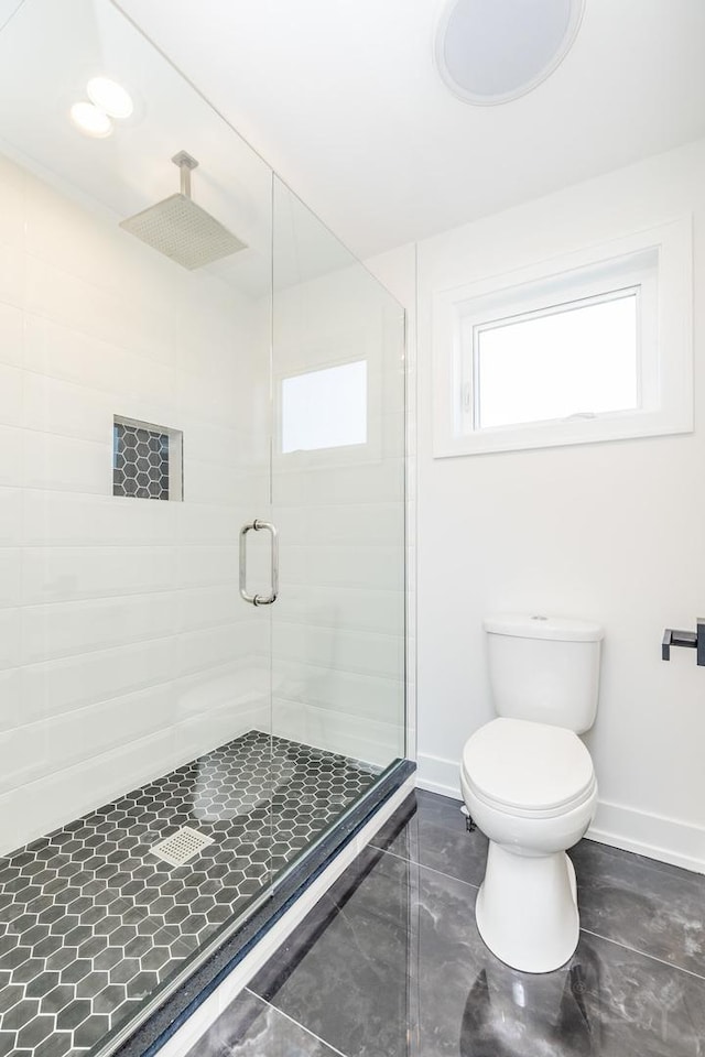 full bathroom featuring toilet, a stall shower, and baseboards