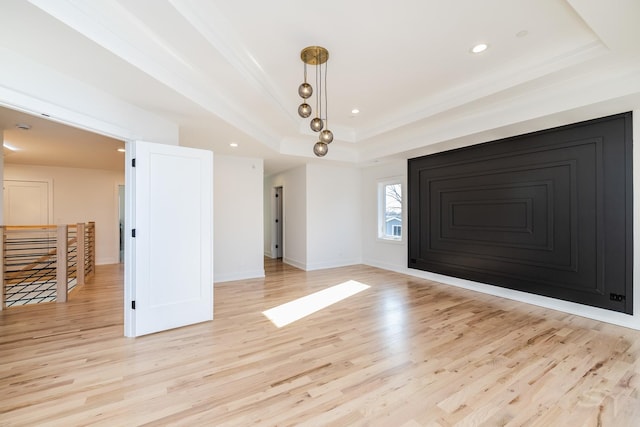 interior space featuring a tray ceiling, crown molding, recessed lighting, light wood-type flooring, and baseboards