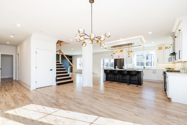 kitchen featuring a center island, recessed lighting, freestanding refrigerator, light wood-type flooring, and a kitchen bar