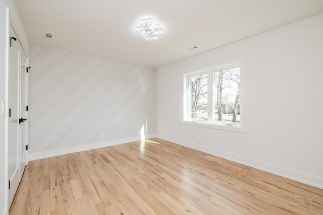 spare room with visible vents, light wood-style flooring, and baseboards