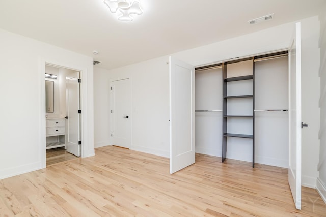 unfurnished bedroom featuring ensuite bathroom, light wood finished floors, visible vents, and baseboards