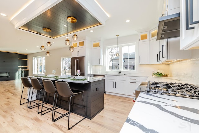 kitchen with light wood finished floors, decorative backsplash, high end fridge, and decorative light fixtures