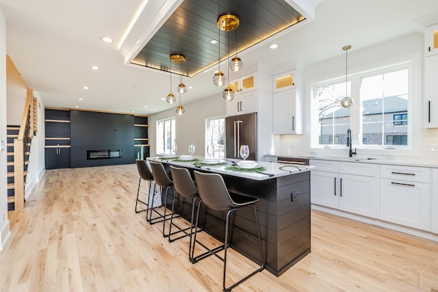 kitchen featuring a center island, a fireplace, light wood finished floors, high quality fridge, and a sink