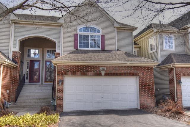 traditional-style home featuring a shingled roof, brick siding, driveway, and an attached garage