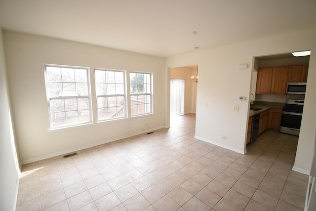 interior space with a chandelier, light tile patterned floors, a sink, visible vents, and baseboards