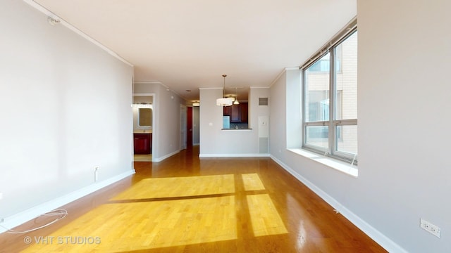 unfurnished living room with crown molding, baseboards, and light wood-style floors