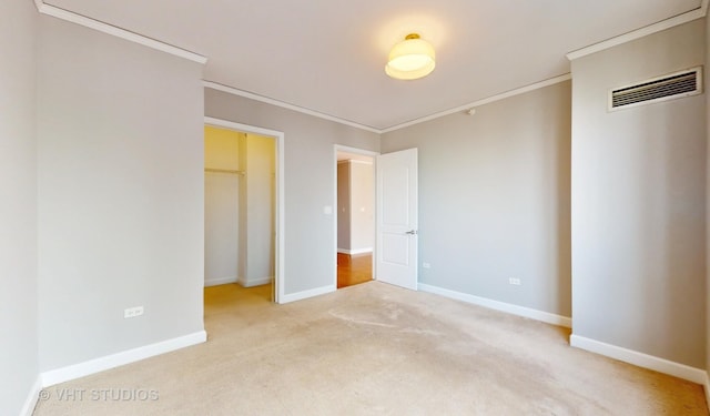 unfurnished bedroom featuring carpet, visible vents, crown molding, and baseboards