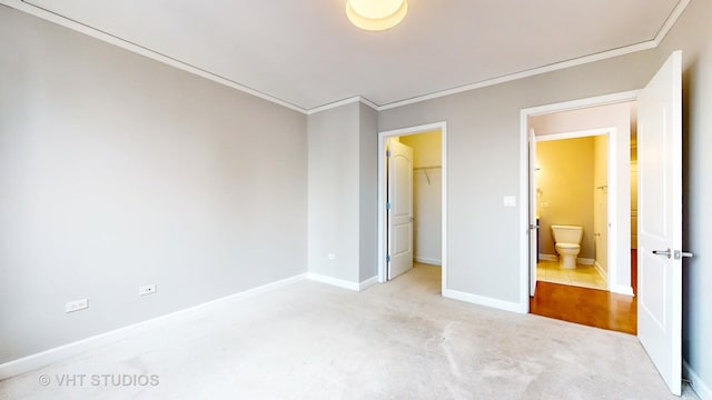 unfurnished bedroom featuring carpet, a walk in closet, crown molding, a closet, and baseboards