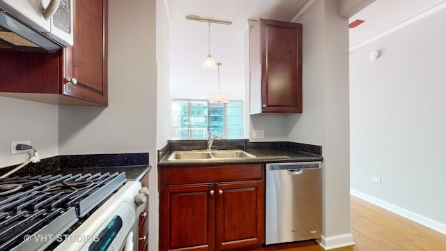 kitchen featuring a sink, light wood-style floors, hanging light fixtures, stainless steel dishwasher, and dark countertops