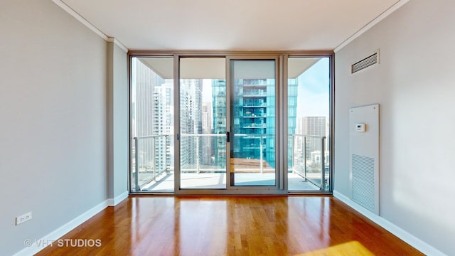 spare room with baseboards, ornamental molding, wood finished floors, and floor to ceiling windows