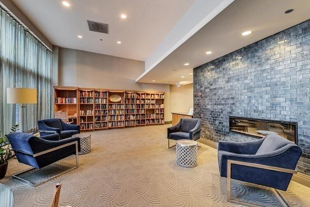 sitting room with recessed lighting, visible vents, a glass covered fireplace, carpet flooring, and wall of books