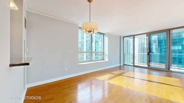 unfurnished room featuring crown molding, wood finished floors, and baseboards