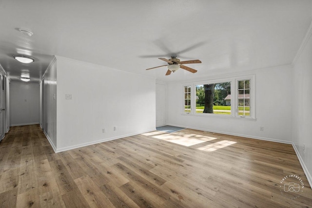 empty room with crown molding, wood finished floors, a ceiling fan, and baseboards