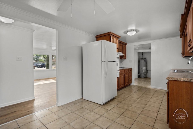 kitchen featuring water heater, ornamental molding, a sink, and freestanding refrigerator