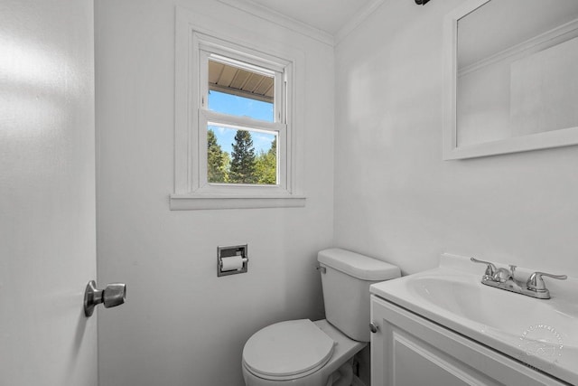 half bathroom featuring ornamental molding, vanity, and toilet