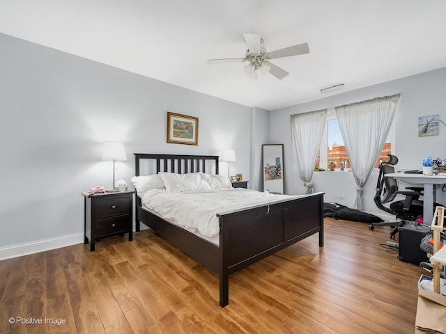 bedroom with a ceiling fan, wood finished floors, and baseboards