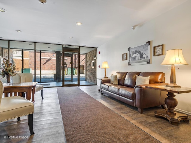 living room featuring recessed lighting, a wall of windows, baseboards, and wood finished floors