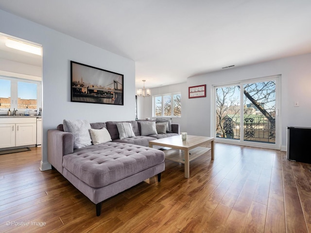 living area featuring wood finished floors, visible vents, and a chandelier