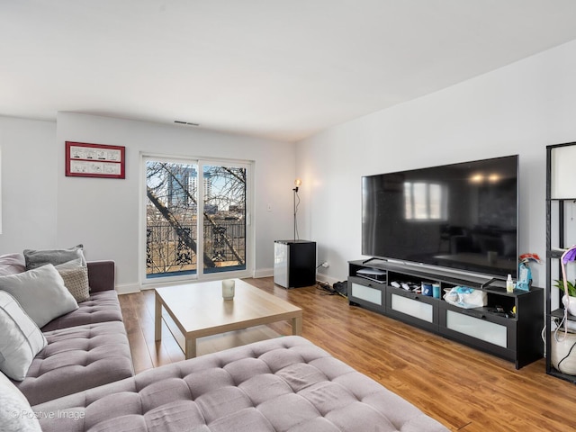 living area with visible vents, baseboards, and wood finished floors