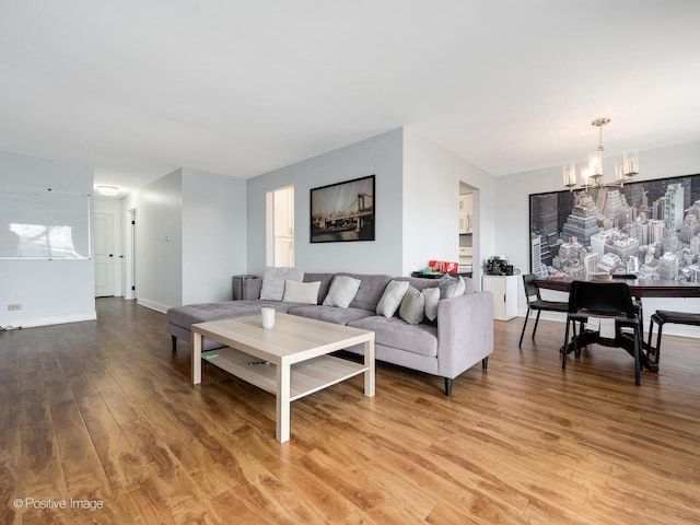 living area featuring a notable chandelier, light wood-style flooring, and baseboards