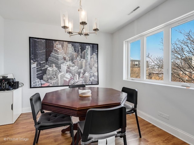 dining space featuring visible vents, baseboards, an inviting chandelier, and wood finished floors