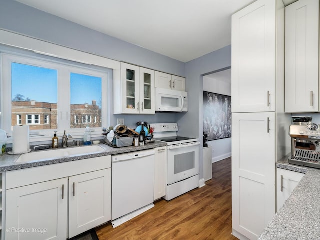 kitchen with white cabinetry, white appliances, and a sink