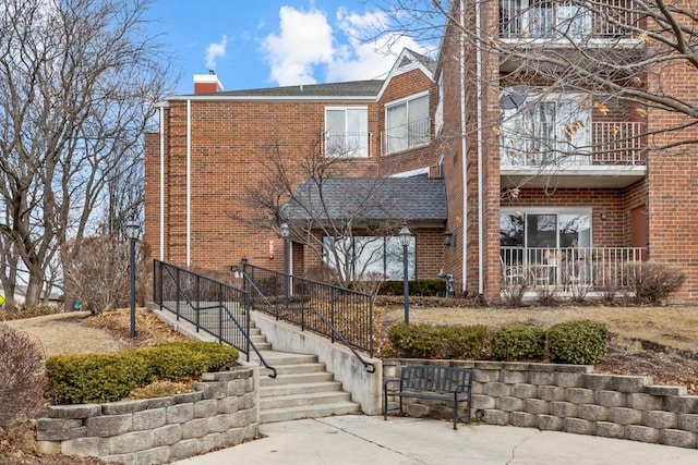 exterior space featuring brick siding, a chimney, and a balcony