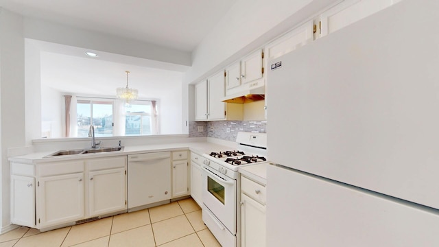 kitchen featuring under cabinet range hood, light countertops, decorative backsplash, white appliances, and a sink